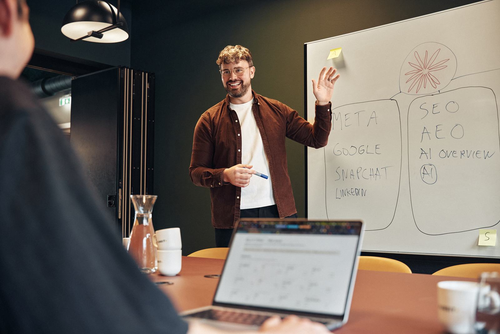En smilende rådgiver som holder en presentasjon om AI og moderne markedsstrategi på en tavle hos Funbit