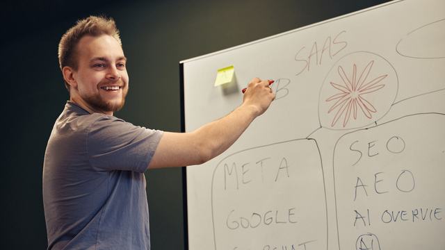 Funbit utvikler som visualiserer et komplekst teknisk poeng på en whiteboard under en felles idemyldring