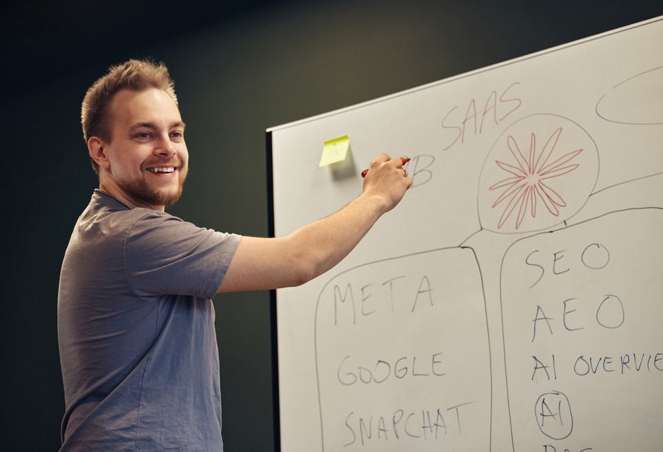 Funbit utvikler som visualiserer et komplekst teknisk poeng på en whiteboard under en felles idemyldring